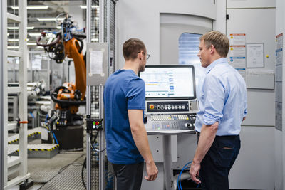 Businessman and employee standing at control panel in a factory