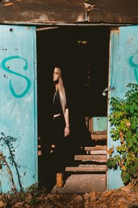 Full length of woman standing at entrance of abandoned building