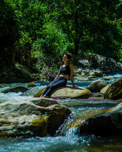Woman sitting on rock in river