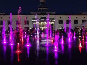 Illuminated fountain with buildings in background