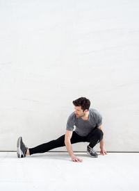 Full length of young man sitting on wall