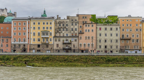 Residential buildings by river against sky