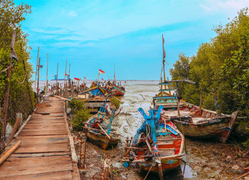 Fishing boats moored on beach against sky