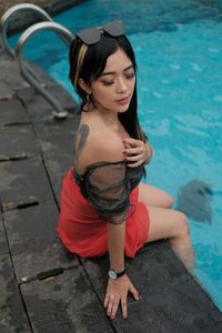 Portrait of young woman sitting in swimming pool