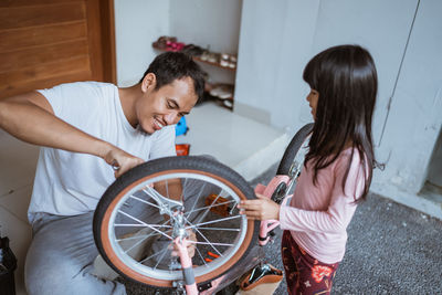 Smiling father with daughter repairing bicycle