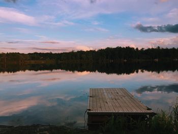 Pier on lake against sky during sunset