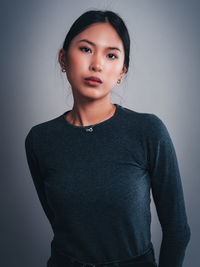 Portrait of young woman standing against wall