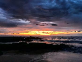 Scenic view of sea against dramatic sky during sunset