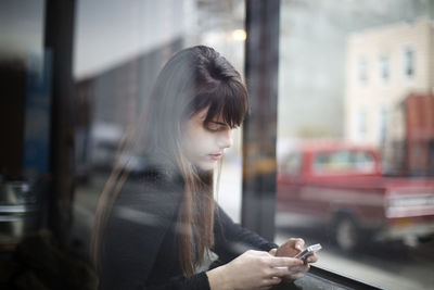 Young woman looking away while standing on street in city