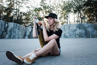 Woman holding her skateboard looking at the sunset at a skate park