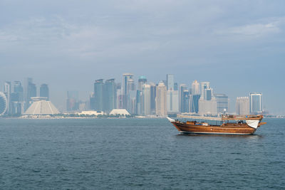 A traditional dhow in doha, qatar with the city's modern skyline in the background.