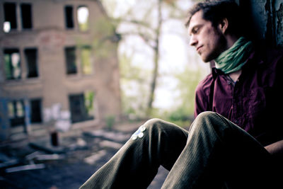 Mid adult man sitting at window against building