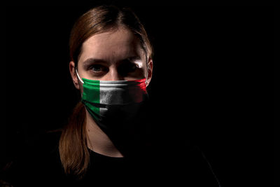 Portrait of young woman against black background