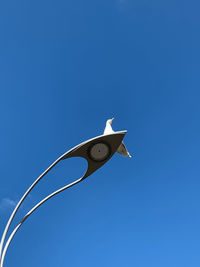 Low angle view of a bird against clear blue sky