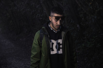 Young man wearing sunglasses standing against trees