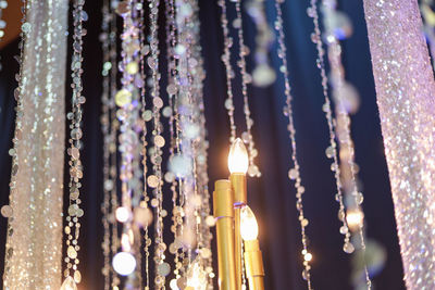 Close-up of illuminated lighting equipment hanging at night