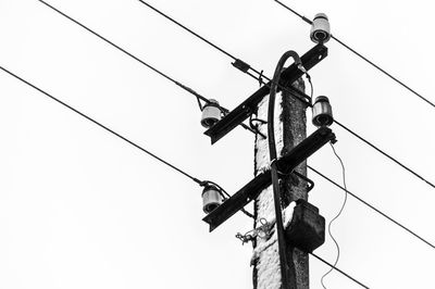 Low angle view of electricity pylon against clear sky