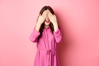 Woman standing against pink background