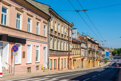 Road by buildings against blue sky