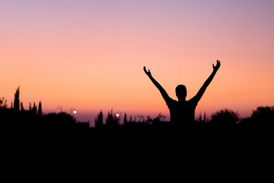 Silhouette man standing on rock against sky during sunset