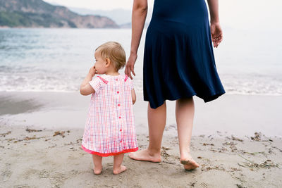 Rear view of mother and daughter standing on beach