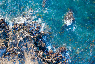 Top-down view of crystal clear sea water hitting rocks