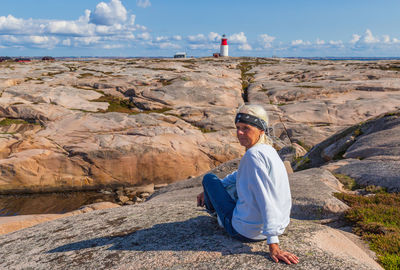 Woman sitting on rock in sunny day
