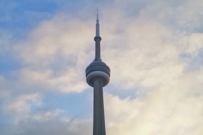 Low angle view of communications tower and building against sky