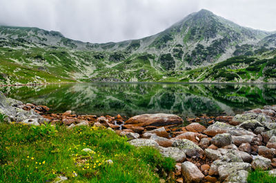 Scenic view of rocky mountains by lake against sky