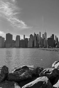 Sea by buildings in city against sky