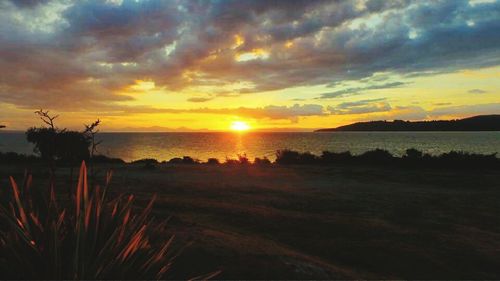 Scenic view of sea against dramatic sky during sunset