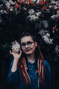 Portrait of young woman standing by plants