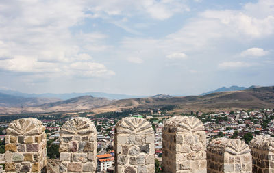 Houses in town seen through from fort against cloudy sky