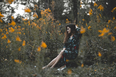 Woman sitting amidst plants in forest