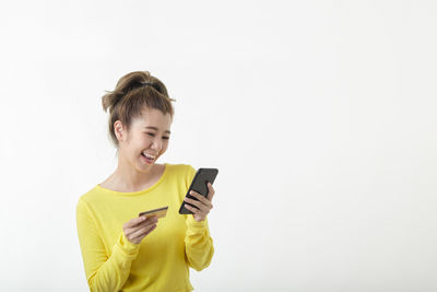Smiling young man using smart phone against white background