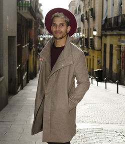 Fashion young model with grey jacket and red hat in city