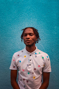 Portrait of young man standing against blue wall