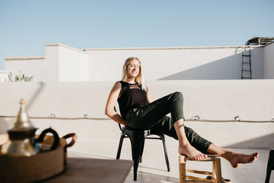 Portrait of woman sitting on chair against clear sky