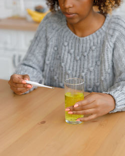 Midsection of woman holding drink on table