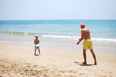 Rear view father and son playing at beach
