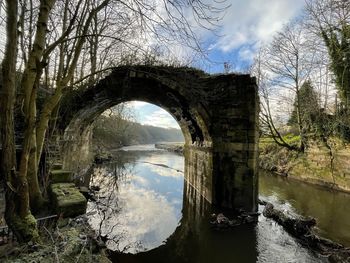 Arch bridge over river against sky