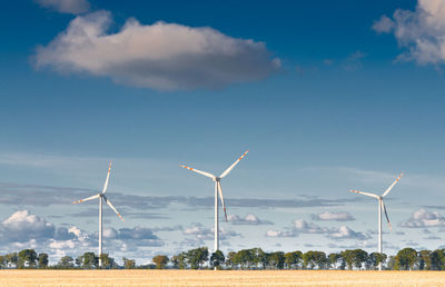 Wind turbines on field against sky