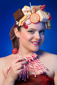 Portrait of woman eating waffle against blue background