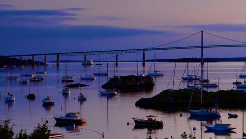Sailboats moored in sea against sky at sunset