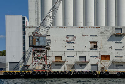 Industrial building by pier against sky