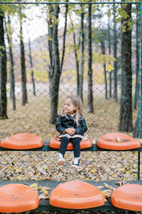 Side view of woman sitting on swing in forest