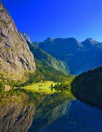 Scenic view of lake and mountains against clear blue sky