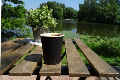 Coffee cup on table by lake