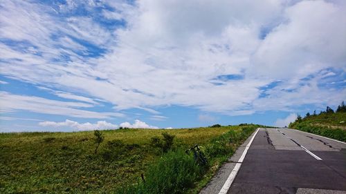 Road amidst field against sky