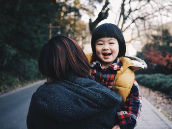 Mother carrying happy daughter